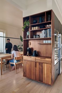 a woman sitting at a table in front of a book shelf