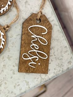 three wooden tags with the word coors hanging from strings on a table top next to other ornaments