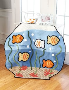 a crocheted rug with fish and bubbles on the floor in front of a window