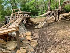 a wooden bridge in the middle of a forest with rocks and trees around it,