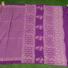 a purple and white sari with floral designs on it, laying on the ground