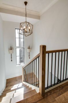 an empty staircase with wooden handrails and chandelier