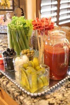 several jars filled with different types of food on a counter top next to an assortment of fruits and vegetables