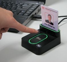 a person is pointing at a business card holder on a desk with a laptop in the background