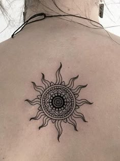 a woman's back with a sun tattoo on it