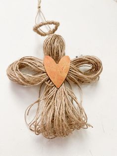 a cross made out of twine with a wooden heart hanging from it's center