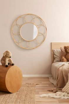 a teddy bear sitting on top of a wooden table in front of a round mirror