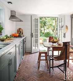 a kitchen with an open door leading to the dining room and patio area, along with brick flooring