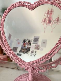 a pink heart shaped mirror sitting on top of a table