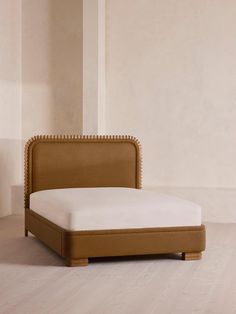 an upholstered bed frame with studded headboard and foot board in a room