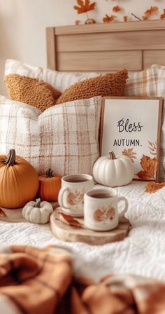 a bed topped with pillows and cups filled with fall leaves next to a sign that says, blessing autumn