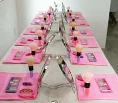 a long table with pink placemats and makeup brushes on top of each other