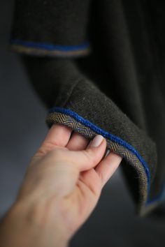 a person holding something in their hand with blue stitching on the side of it