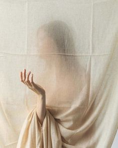 a woman with her hands on the back of a white cloth draped over her head