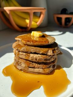 a stack of pancakes sitting on top of a white plate covered in syrup and butter