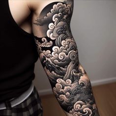 a man's arm with clouds and mountains on it