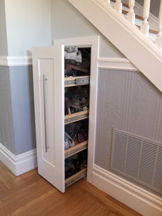 an under the stairs storage area with shoes and other items in it, next to a stair case