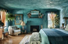 a bedroom with green walls and blue bedding in the corner, along with a fireplace