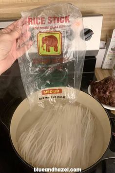 rice sticks being cooked in a wok on the stove top with a plastic bag over it