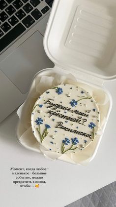 there is a cake in a plastic container on the table next to a laptop computer