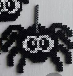 two black and white beaded spider ornaments hanging from a hook on a refrigerator door