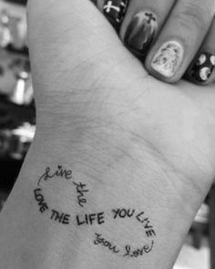 a person's wrist with some writing on it and a clock in the middle