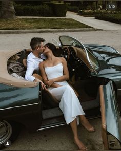 a man and woman sitting in the back of a convertible car with their feet on the hood