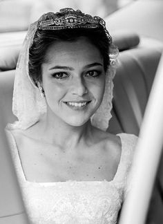 a woman in a wedding dress and veil sitting in a car looking at the camera