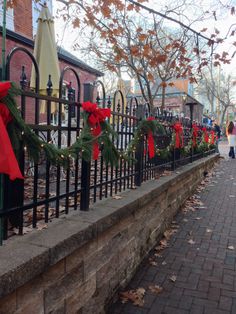 christmas wreaths are tied to the iron fence