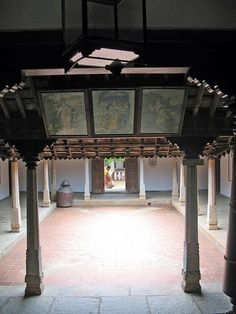 an empty room with pillars and paintings on the walls