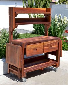 a wooden shelf sitting on top of a sidewalk next to a potted planter