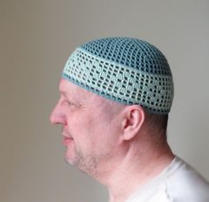 a man with a crocheted hat on his head looking off to the side