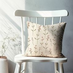 a white chair with a pillow on top of it next to a potted plant