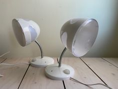 two white lamps sitting on top of a wooden table next to each other with wires coming out of them