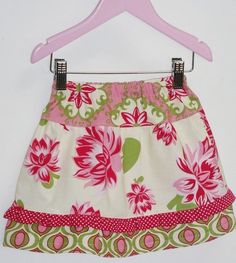 a pink and green flowered skirt hanging on a hanger