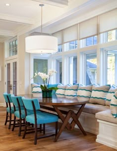 a dining room table with blue chairs around it and a large window in the background