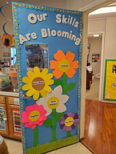 a classroom door decorated with paper flowers and writing on the doors says our skills are blooming