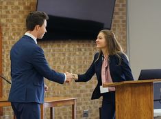 two people shaking hands in front of a podium