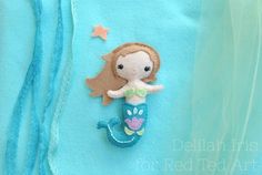 there is a felt mermaid on the back of a blue shirt with stars and seaweed