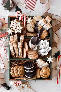 an open box filled with cookies and other holiday treats on top of a white table