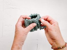 two hands are holding yarn and crochet together to make a flower ornament