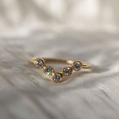 a gold ring with three different colored stones on it's side, sitting on a white sheet