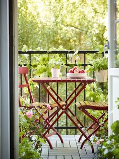 an outdoor table with two chairs next to it and potted plants on the balcony