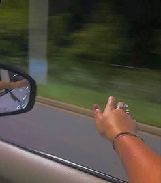 a person's hand on the side mirror of a car as it drives by