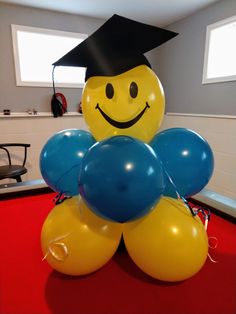 balloons are arranged in the shape of a smiley face with a graduation cap on top