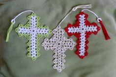 three crocheted crosses hanging on a green blanket