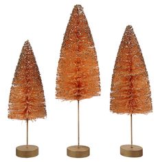 three small trees are shown in orange tinsel