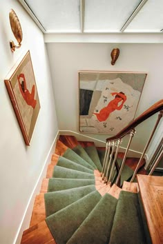 a spiral staircase in a home with artwork on the wall and wooden steps leading up to the second floor