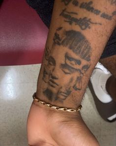 a man's arm with tattoos on it and a gold chain around his wrist