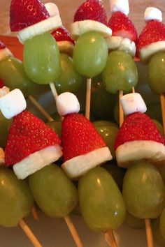 green grapes and strawberries with santa hats on them are arranged in a bowl for an appetizer